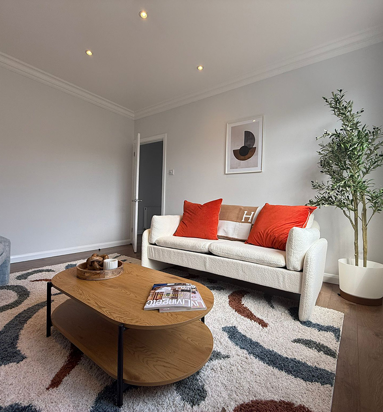 Circular dining table with tablewear and a blue sofa in the background, staged by Velvet Property Staging
