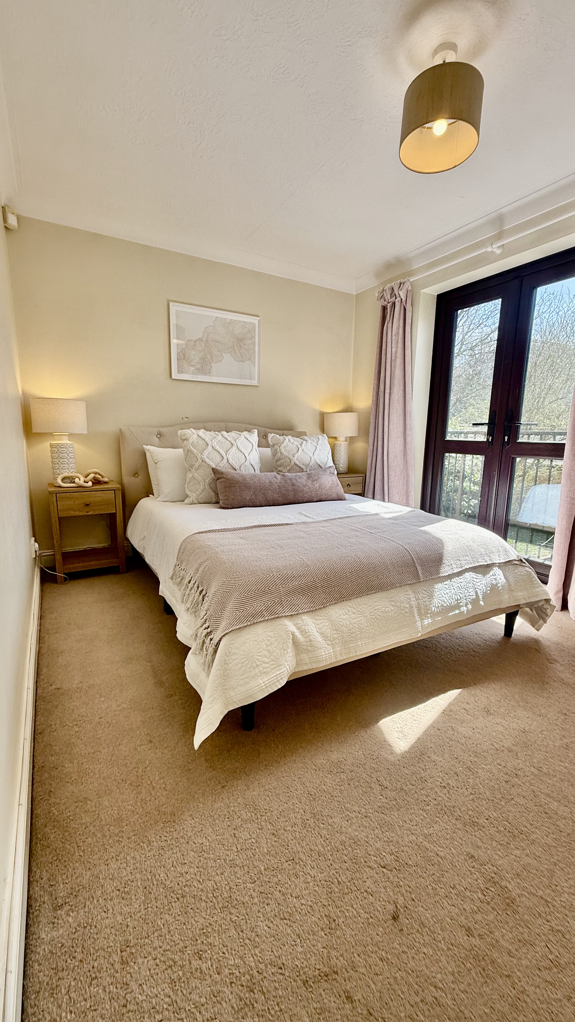 White bed in a white room with 6 butterfly photos on the wall